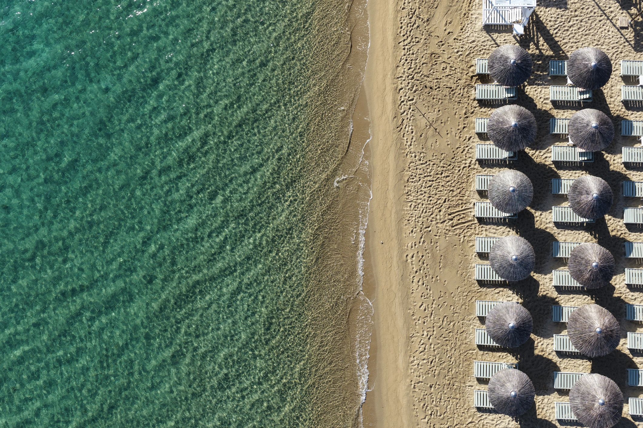 Aerial view of beach umbrellas beside turquoise water